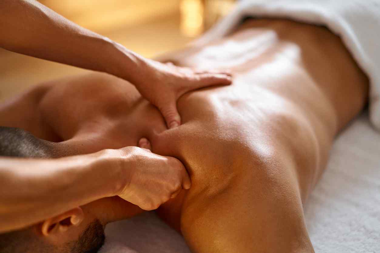 Mann mottar massasje liggende på massasjebenk